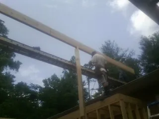 Carpenter setting a ridge beam over a new addition frame — Ice Dam Removal by Roofing Brothers in Onawa