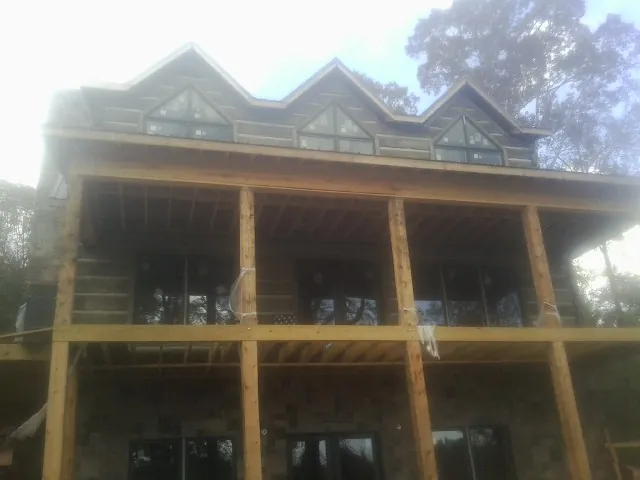 Dormers and porch framing on a large log home under construction — Roof Coating work by our crew in Onawa