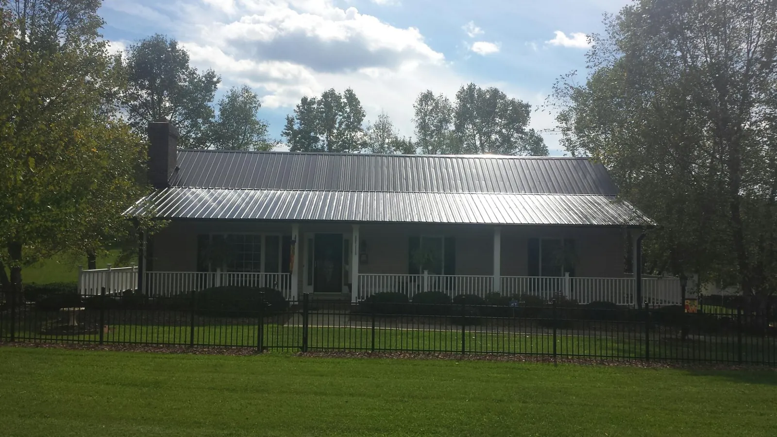 Gray metal roof on a brick ranch with a full width front porch — Gutter Guard Installation work by our crew in Onawa