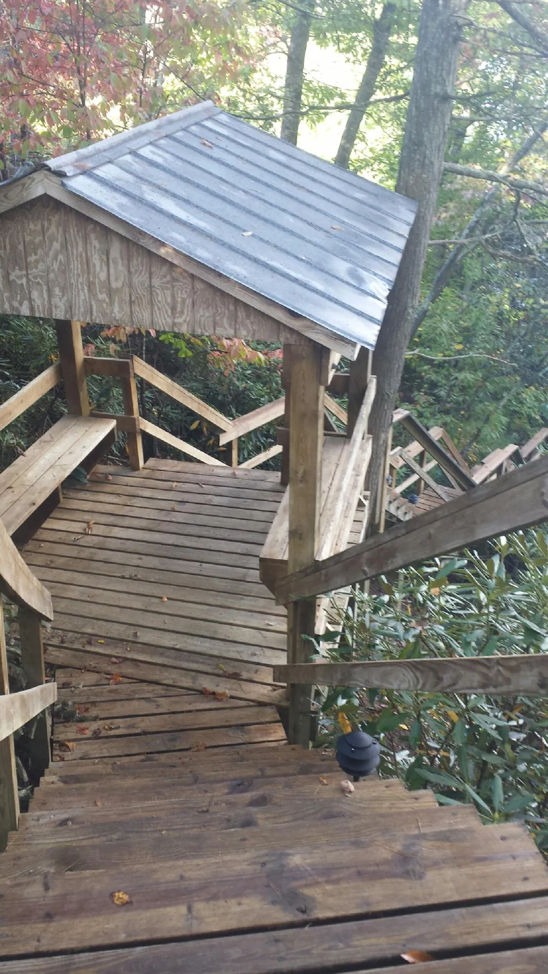 Metal roofed shelter over wooden steps on a wooded walkway — Skylight Repair & Installation work by our crew in Onawa