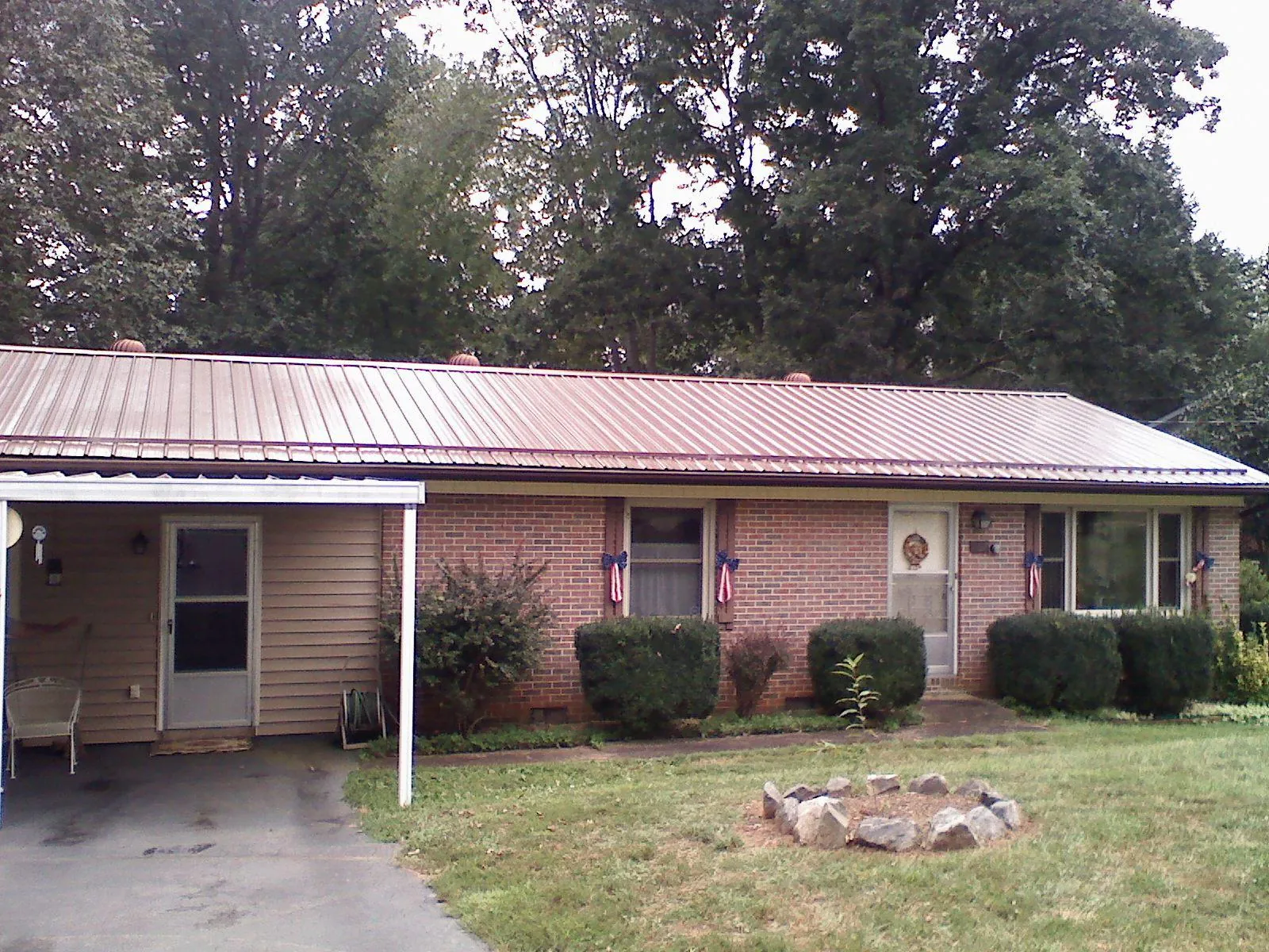 Bronze metal roof and carport on a brick ranch home — Roof Repair work by our crew in Onawa
