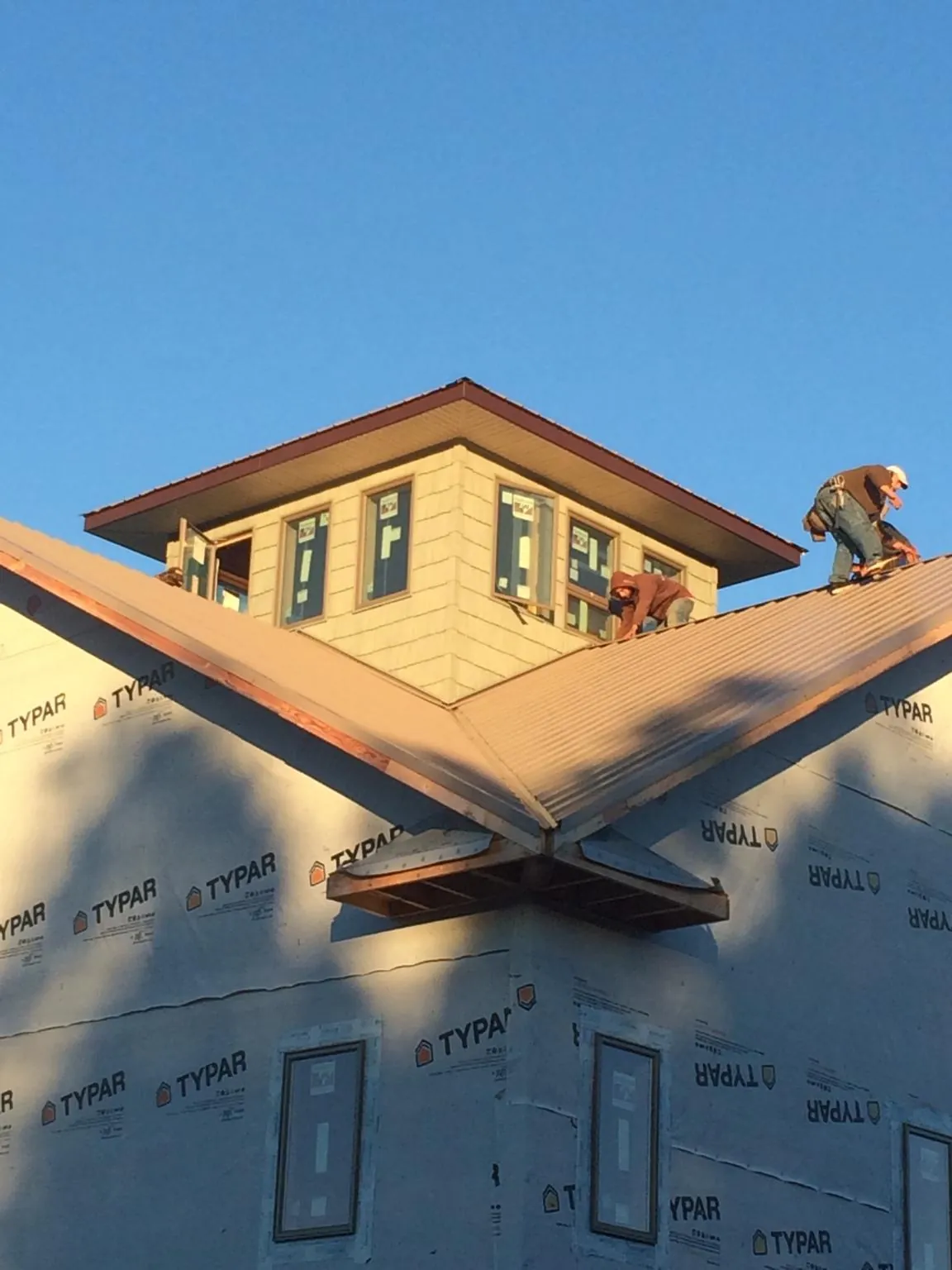 Roofers working around a rooftop cupola on a new metal roof at sunset — Roof Waterproofing in Onawa by Roofing Brothers